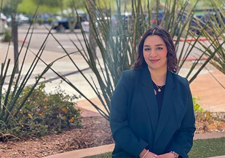 Danya Delgadillo in a blue blazer sitting in front of desert plants.