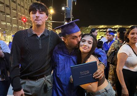 Frank Nino posing with his two children at commencement