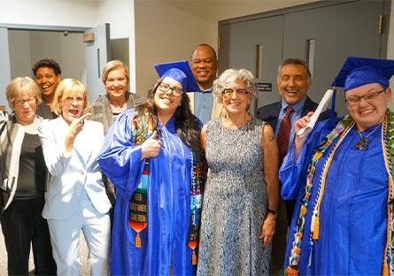 HSE graduate speakers with President Kate Smith and MCCCD Governing Board Members behind stage before the ceremony