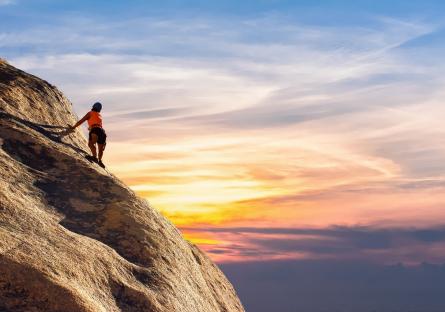 A woman climbing a mountain at sunset