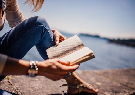 Woman reading a book by the lake