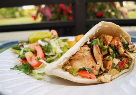 A chicken pita sandwich garnished with vegetables