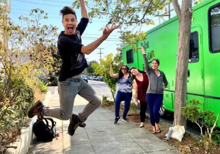 photo of Robert Dekkers jumping. Three Roadtrip Nation students in the background standing by a green RV