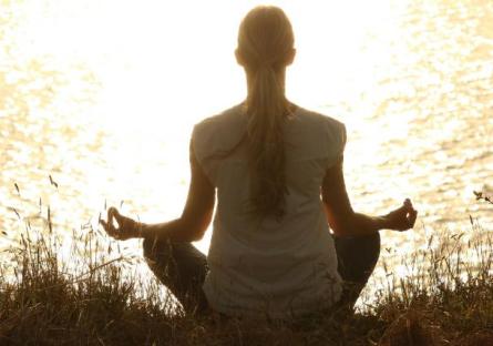 A woman meditating by a lake