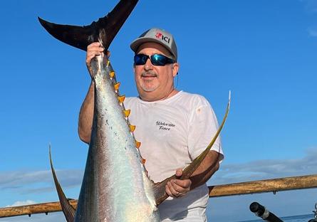 photo of Rick Vaughn on a boat, holding up a tuna he caught