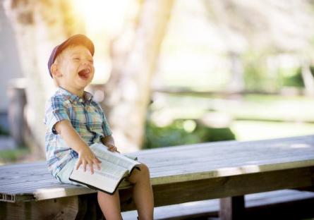 Little boy laughing while holding a book