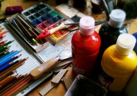 Colored pencils, paint bottles, and paintbrushes